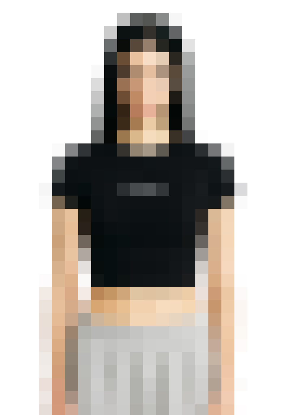 Eine Person steht frontal vor einem weißen Hintergrund. Sie trägt ein schwarzes, kurzärmliges Crop-Top mit einem kleinen Aufdruck auf der Brust und eine hellgraue Hose oder einen Rock.