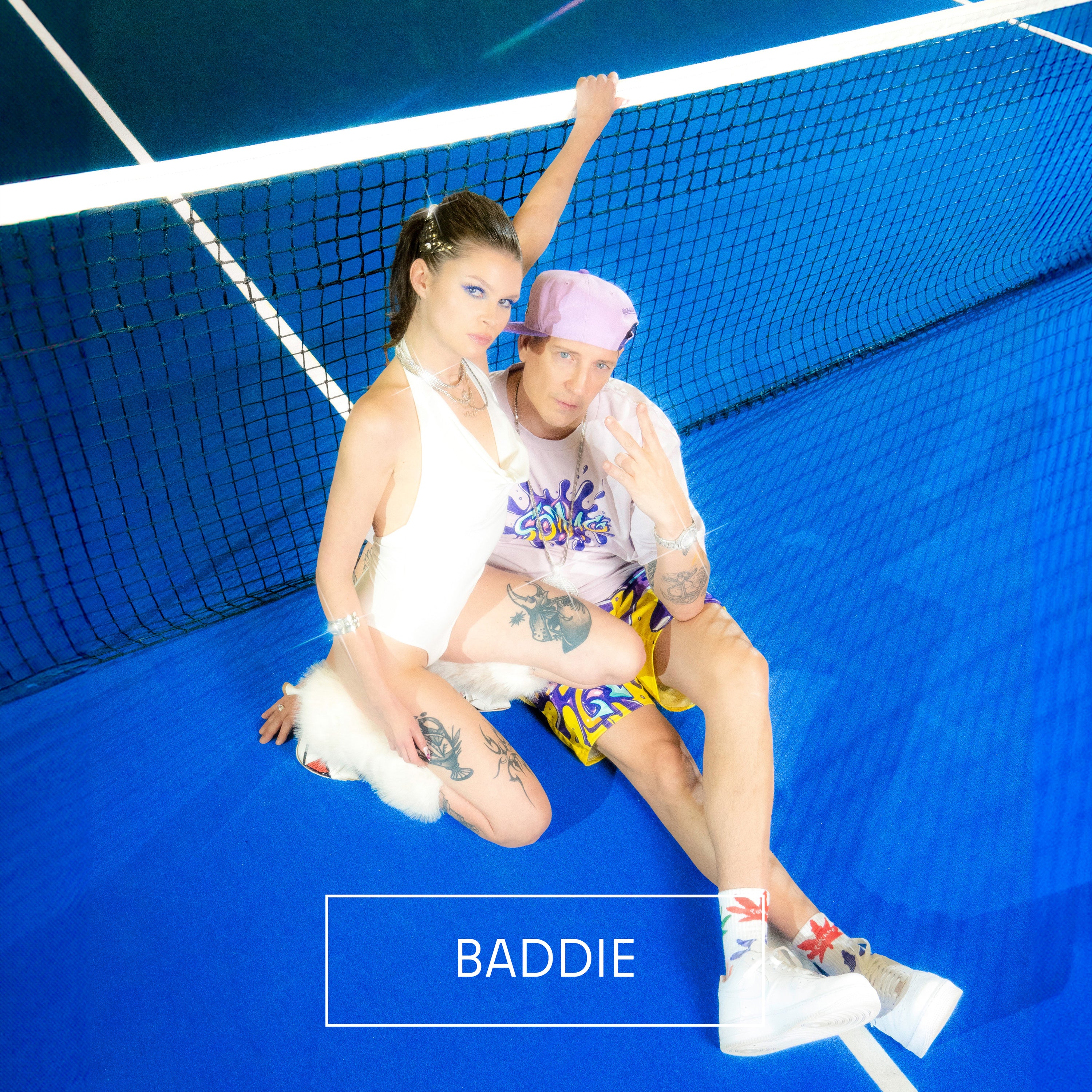 „Covermotiv mit zwei Personen auf einem blauen Tennisplatz. Eine Person trägt einen weißen Badeanzug, die andere ein pastellfarbenes Outfit mit Mütze und Shorts. Unten steht der Titel ‚Baddie‘.“