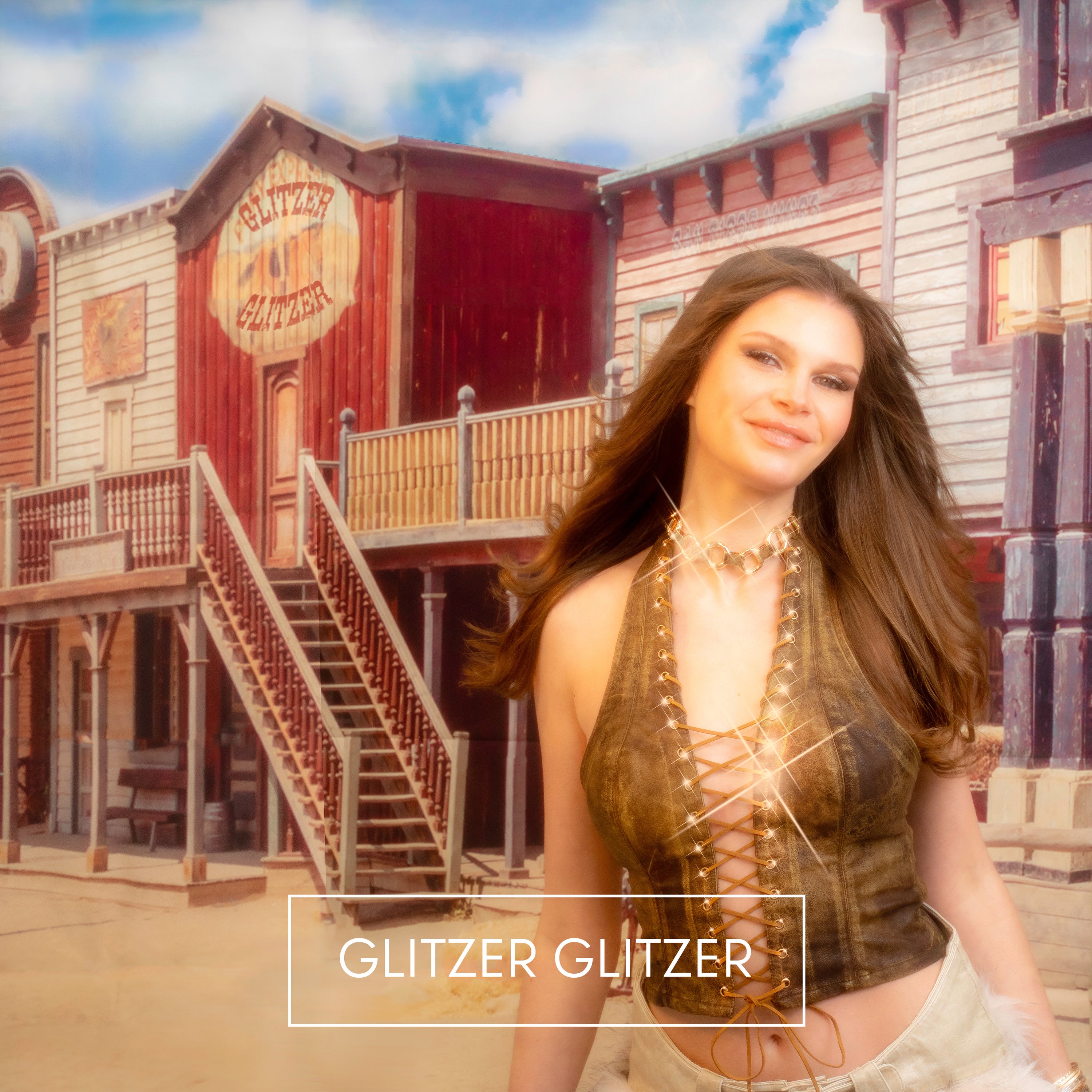 „Frau in braunem, geschnürtem Top und heller Hose steht vor einer Kulisse im Westernstil mit der Aufschrift ‚Glitzer Glitzer‘. Unten der Titel ‚Glitzer Glitzer‘.“